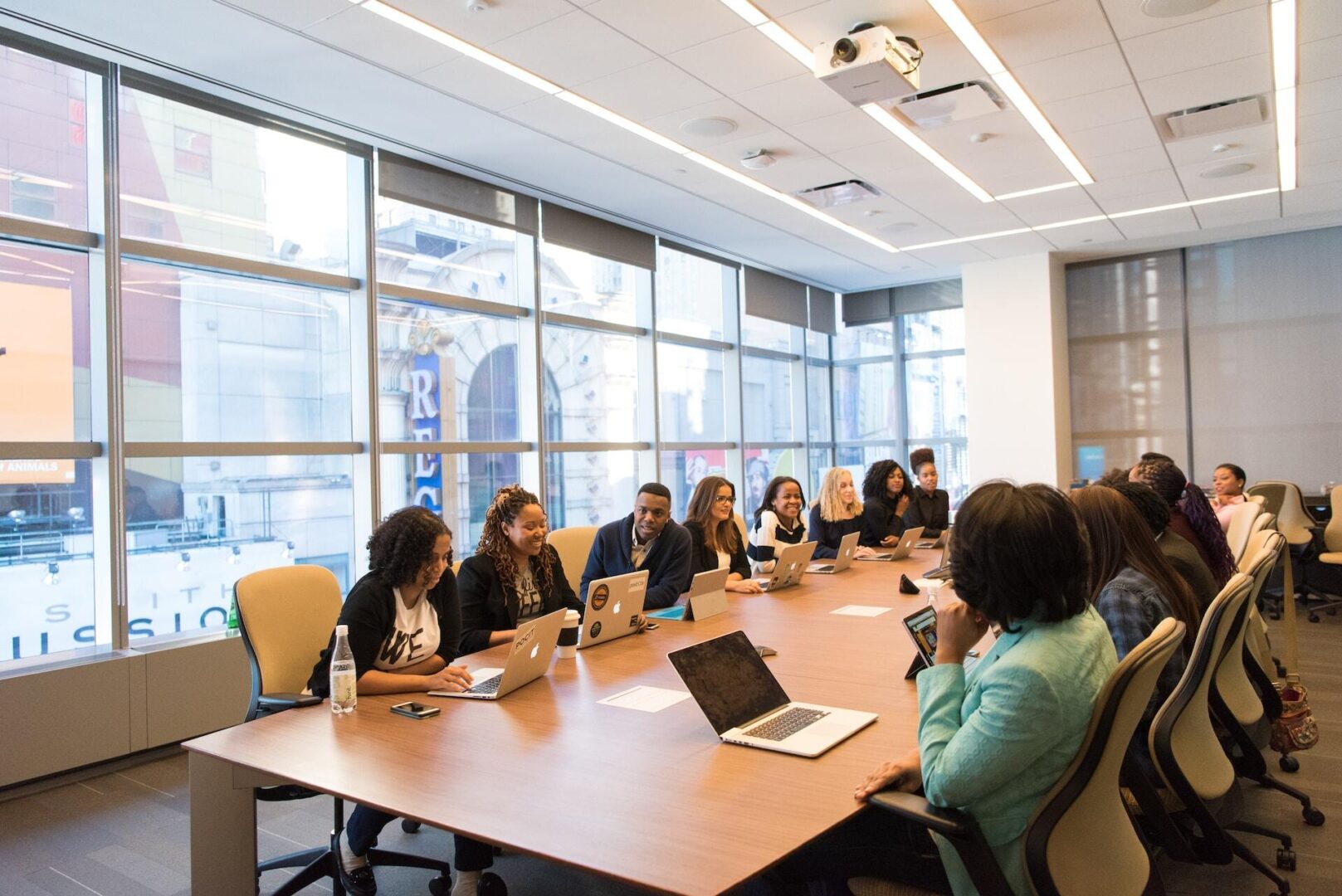 A diverse group of Franchise Tax Board representation professionals engaged in a meeting around a large conference table in a bright, modern office space.