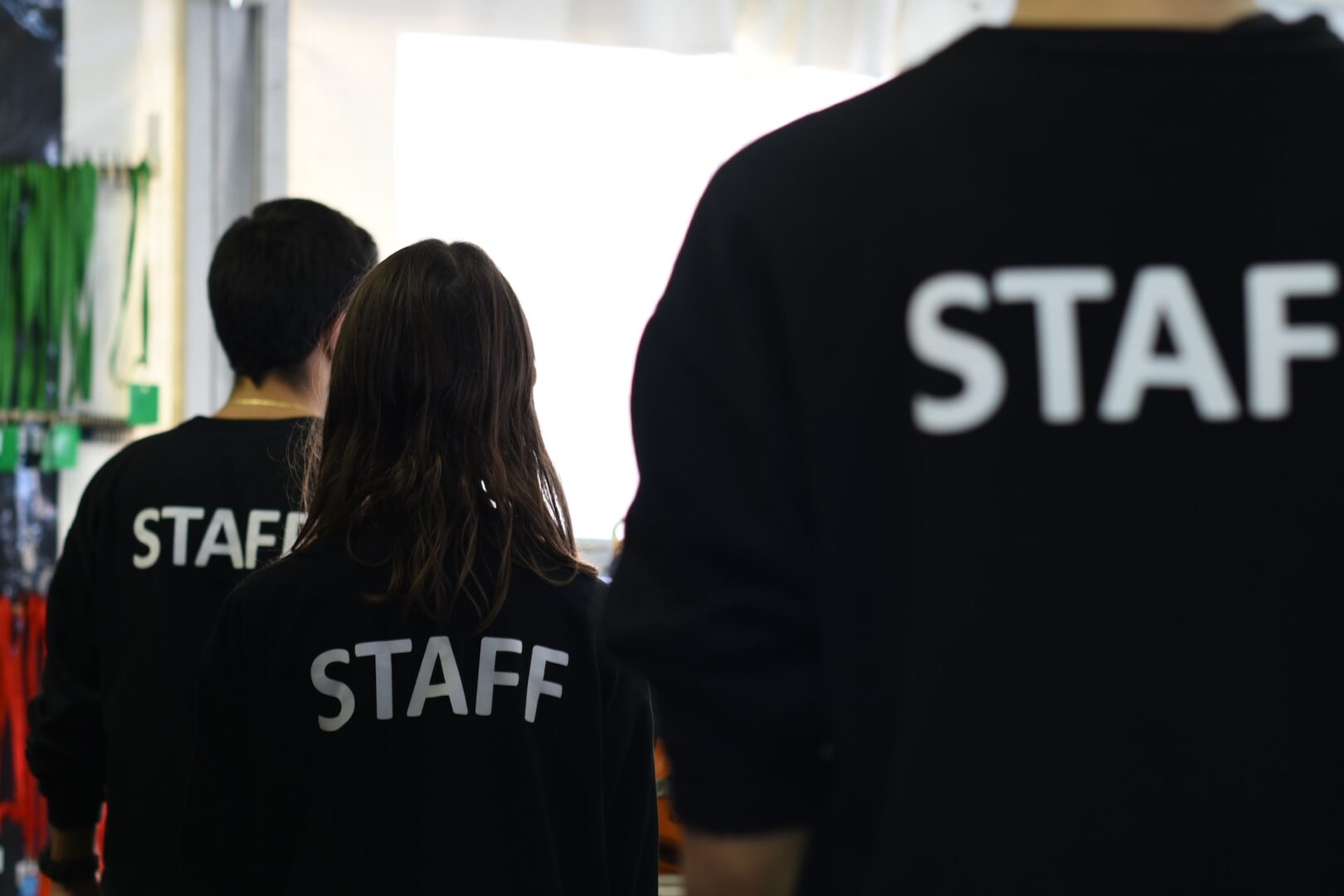 Two event staff members, possibly engaged in ERTC Audits, facing towards a bright light source, at work coordinating an event or production.