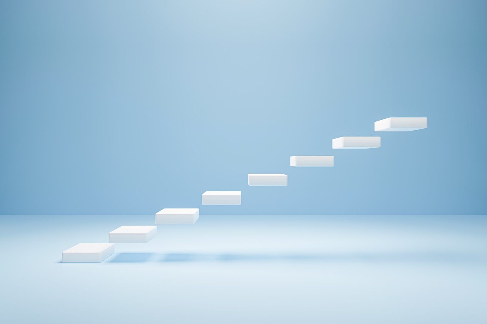 A minimalist image featuring a series of white floating steps arranged diagonally in a light blue, empty space. The steps create the illusion of an abstract staircase leading upwards, evoking a sense of surreal progression and open possibilities. A minimalist image featuring a series of white floating steps arranged diagonally in a light blue, empty space. The steps create the illusion of an abstract staircase leading upwards, evoking a sense of surreal progression and open possibilities.