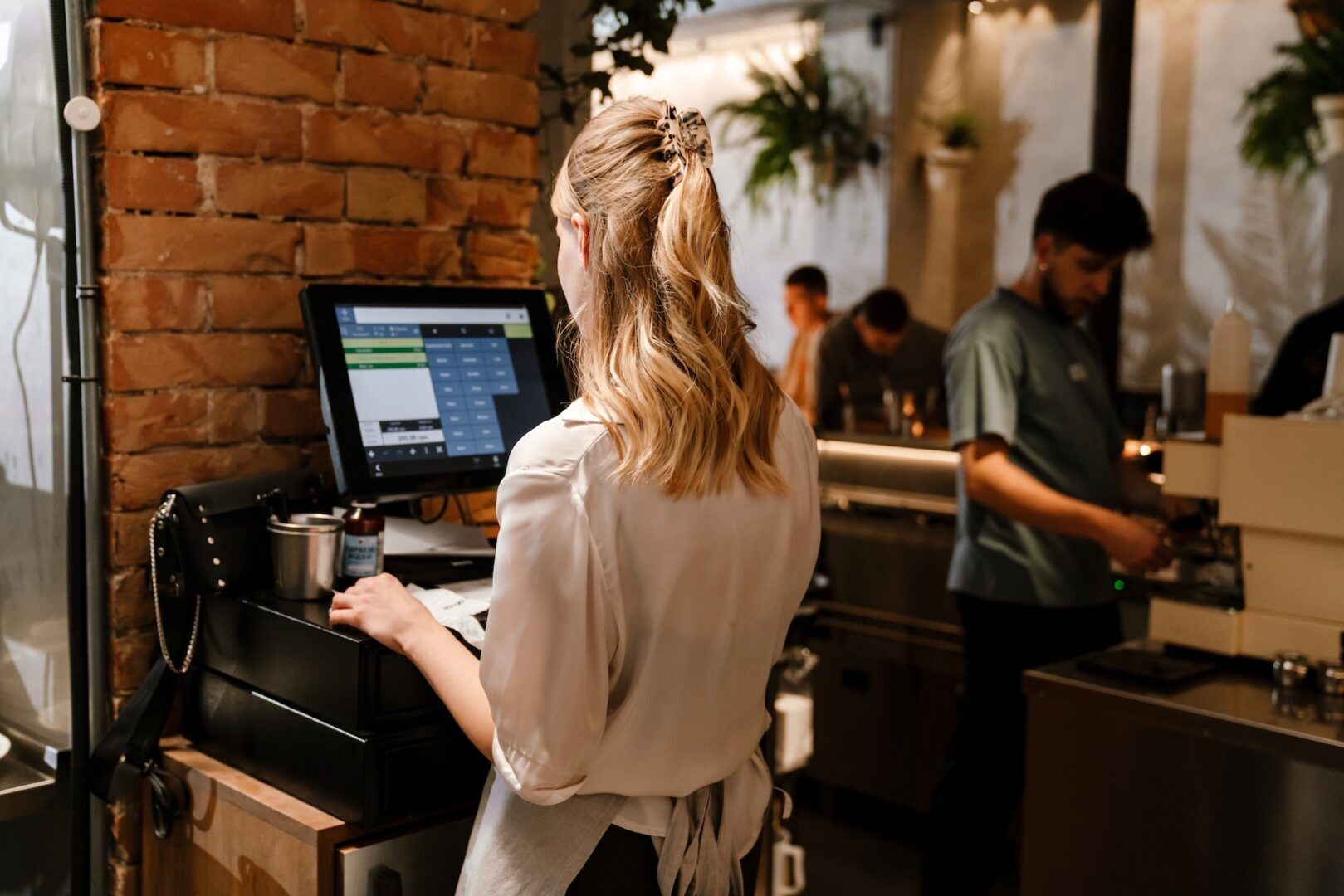 Cashier at a touchscreen register — point-of-sale records CDTFA auditors test against reported taxable sales