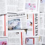 A scattered arrangement of newspapers and magazines featuring various headlines, articles, and images—like "DAILY NEWS" and "BUSINESS REVIEW"—with stories on finance, offices, lifestyle topics, and highlights of Pietro Canestrelli's impact in tax law.