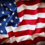 A close-up view of a softly wrinkled American flag, showing the blue field with white stars and red and white stripes, evokes the spirit of American business stars and highlights Pietro Canestrelli's impact in tax law.